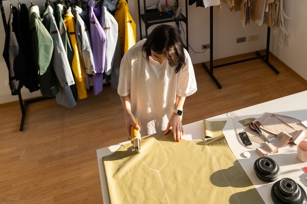 Proceso de costura y corte, modista trabaja con patrones en tela para colección en atelier studio