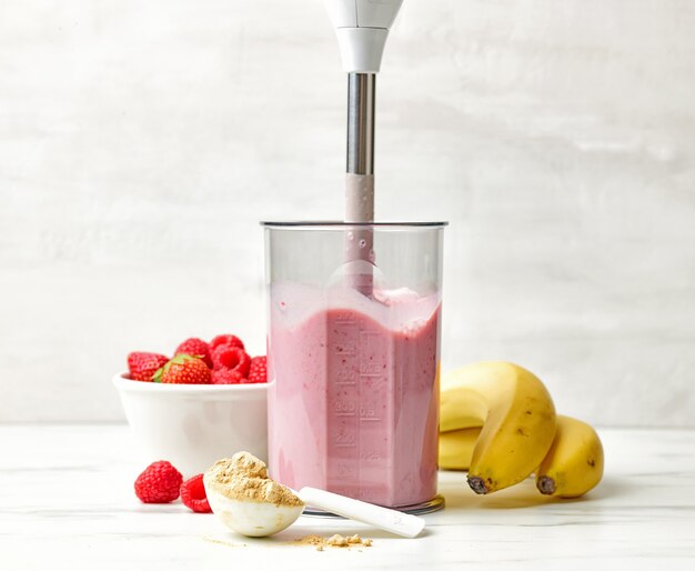 Foto proceso de elaboración de batido de desayuno saludable en la mesa de la cocina