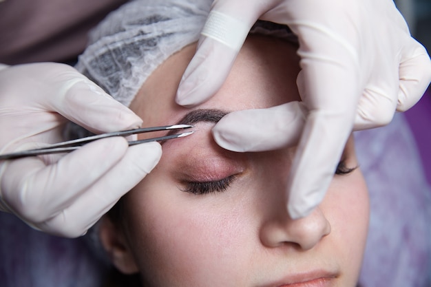 Proceso de elaboración de cejas. Mujer bonita con los ojos cerrados sobre el procedimiento.