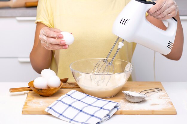 Proceso de elaboración de masa para panqueques con ingredientes en una mesa de luz, los huevos y la harina se baten con una batidora