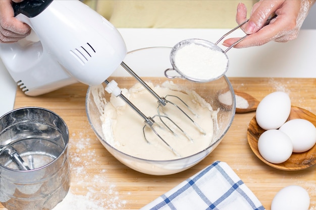 Proceso de elaboración de masa para panqueques con ingredientes en una mesa de luz, los huevos y la harina se baten con una batidora