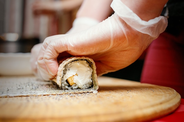 Proceso de elaboración de sushi, rollo de sushi extraño con amapola en un mostrador de madera