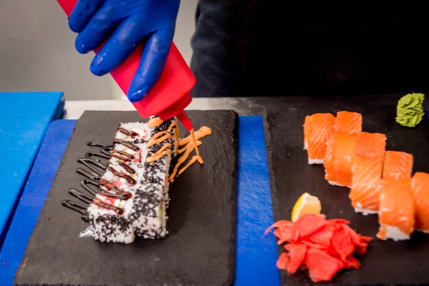 Proceso de elaboración de sushi y rollos en la cocina del restaurante. Chefs manos con cuchillo.