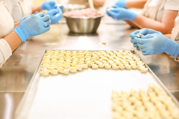 Proceso de fabricación de bolas de masa hervida Manos de empleadores con guantes de goma azul y bolas de masa hervida