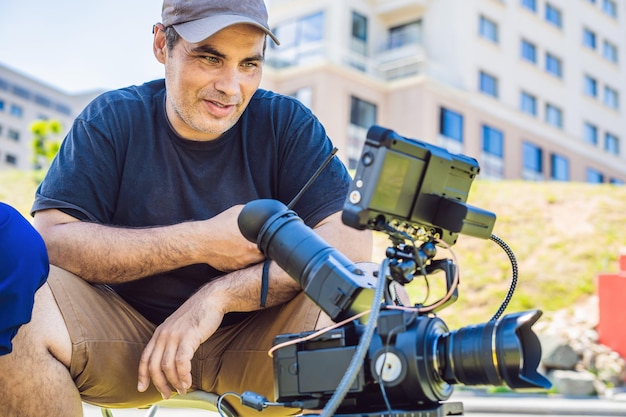 Proceso de filmación en el escenario del cine - set de producción comercial, ubicación exterior. El camarógrafo profesional opera la cámara.