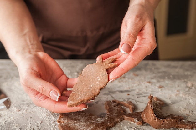 El proceso de hacer pan de jengibre. Manos cortan galletas de jengibre closeup