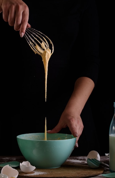 El proceso de hacer pastelitos, cubriendo una crema de una bolsa de pastelería en las manos de un pastelero.