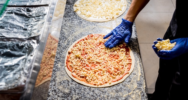 El proceso de hacer pizza. Manos del chef panadero haciendo pizza en la cocina del café