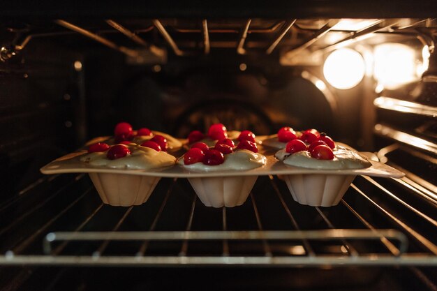 El proceso de hornear cupcakes en el horno Masa para hornear cupcakes con cerezas.