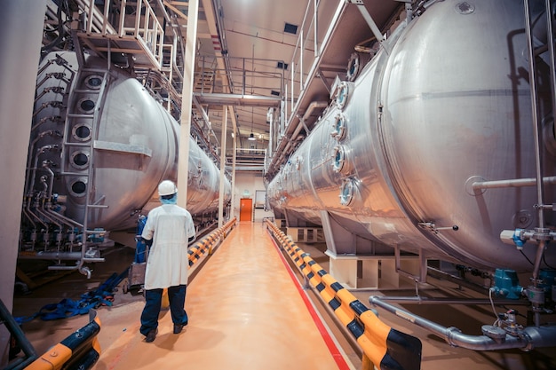 Proceso de inspección de trabajo masculino en bodega de leche en polvo con tanques horizontales de acero inoxidable