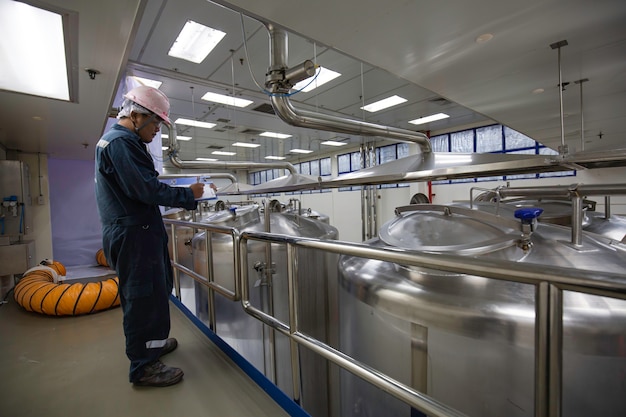 Proceso de inspección de trabajo masculino tanques de acero con tapa inoxidable con medidor de presión en la instalación del tanque del equipo para la bodega de agua en la fábrica con tanques verticales de acero inoxidable