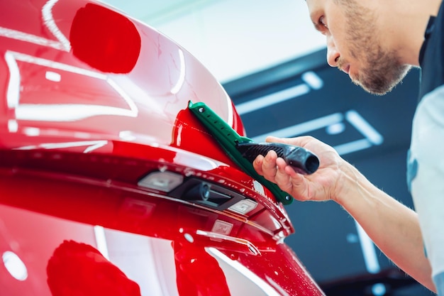 El proceso de instalación de una película protectora en el nuevo coche rojo.