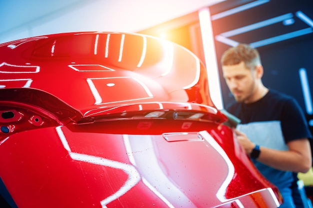 El proceso de instalación de una película protectora en el nuevo coche rojo.