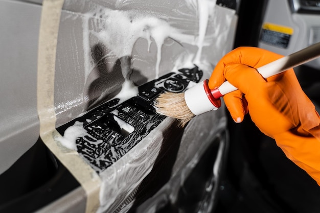 Proceso de limpieza con espuma y detergente con cepillo para el panel de la tarjeta de la puerta del coche Servicio detallado del coche Trabajador en el servicio de limpieza lavado interior del auto del cliente