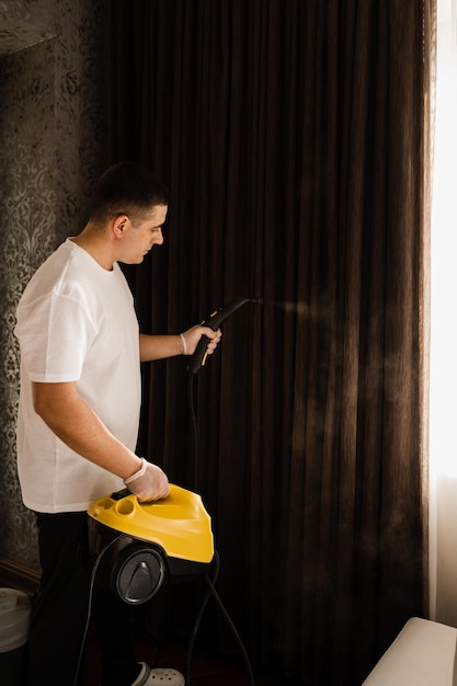 Proceso de limpieza a vapor de cortinas Desinfección y limpieza en seco de cortinas en casa El limpiador vaporiza las cortinas con una máquina de vapor profesional
