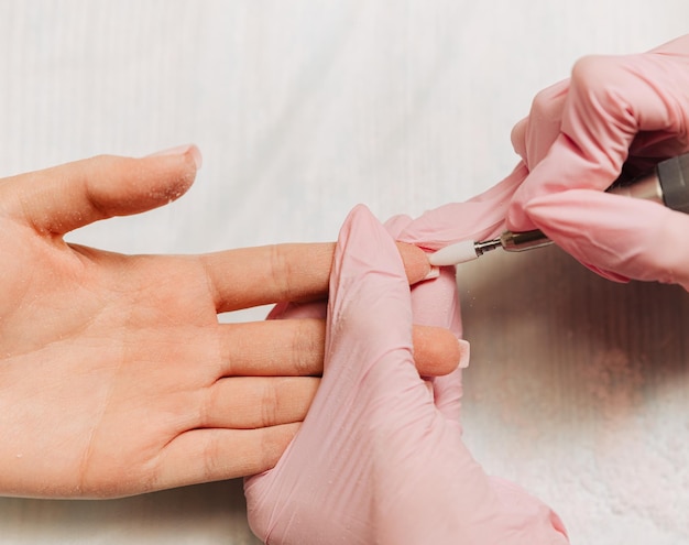 Proceso de manicura El maestro pule la uña usando una máquina automatizada Quitaesmalte de taladro