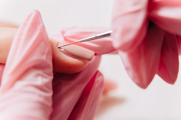 Proceso de manicura. Manicurista pinta las uñas. Esmalte de uñas.