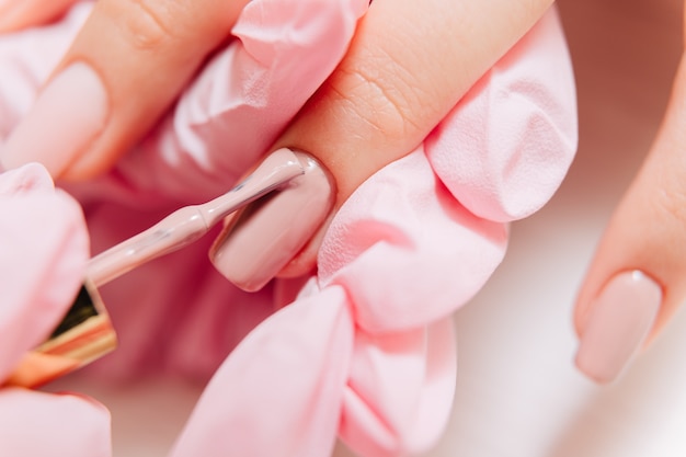 Proceso de manicura. Manicurista pinta las uñas. Esmalte de uñas.