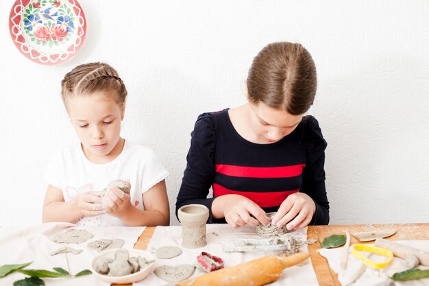 Proceso de modelado de figuras de arcilla blanca, las niñas están haciendo artes en la lección.