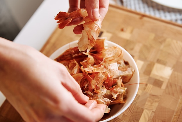 Proceso de pelar las manos de la cáscara de los camarones. Mujer limpiando camarones para cocinar