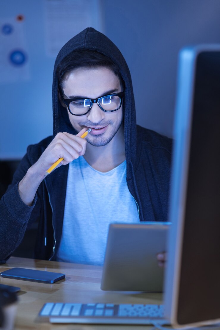 Foto proceso de pensamiento. hombre guapo agradable pensativo mirando la pantalla de la tableta y mordiendo el lápiz mientras busca una solución al problema