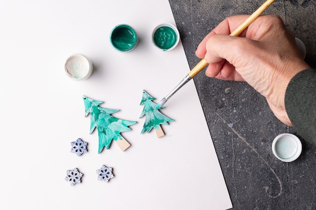 Foto el proceso de pintar juguetes de madera para el árbol de navidad.