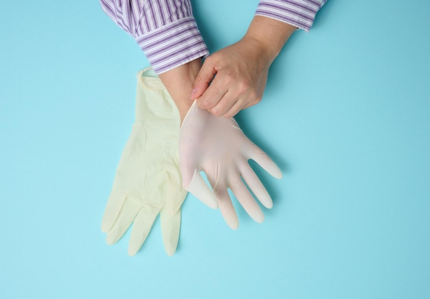 Proceso de poner guantes de látex blancos en la mano sobre fondo azul, protector de higiene