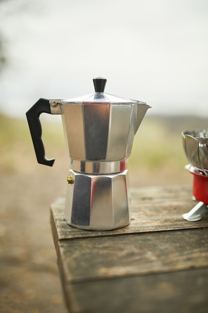 Proceso de preparación de café para acampar al aire libre con cafetera géiser de metal en un quemador de gas, paso a paso.