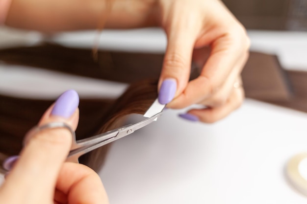 El proceso de preparación de una cinta para el cabello para la extensión en casa. Extensiones de cabello para engrosar el tuyo.