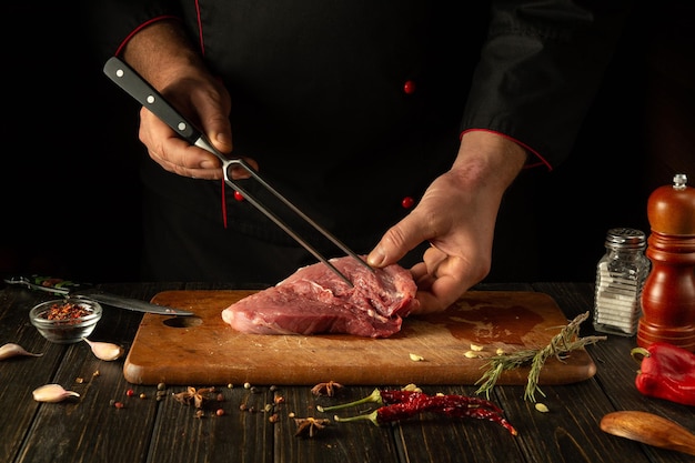 El proceso de preparación de un filete de carne por las manos de un chef en una mesa de la cocina con especias aromáticas Cocinar jugosos y sabrosos shish kebab para el almuerzo o la cena