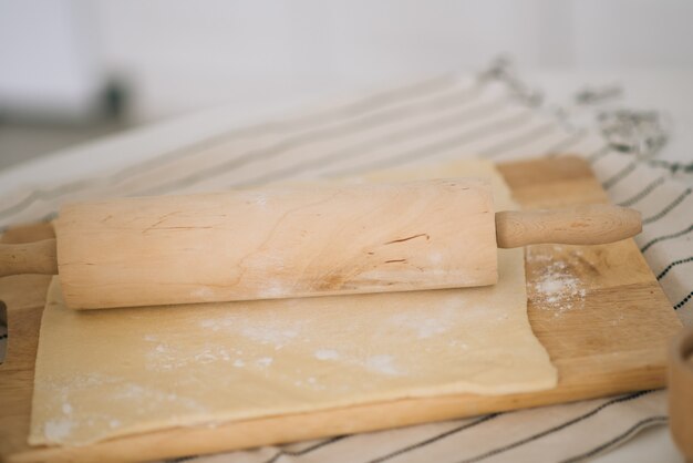 El proceso de preparación de la masa en una tabla de madera con harina dulce en la cocina blanca, enfoque selectivo