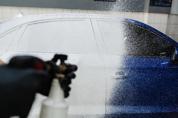 Proceso de rociado de espuma en la carrocería del automóvil en el garaje Segunda fase de lavado detallado en el servicio de automóviles La lavadora de automóviles realiza un lavado de automóviles de cuerpo completo