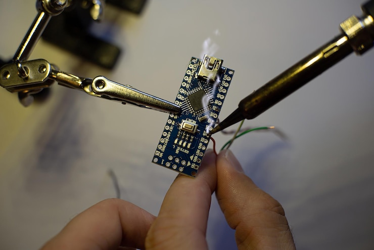 Foto el proceso de soldar cables a una placa arduino nano la abrazadera sujeta la placa
