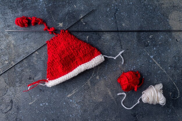 Proceso de tejido de sombreros de Santa Claus sobre un fondo azul paso 1