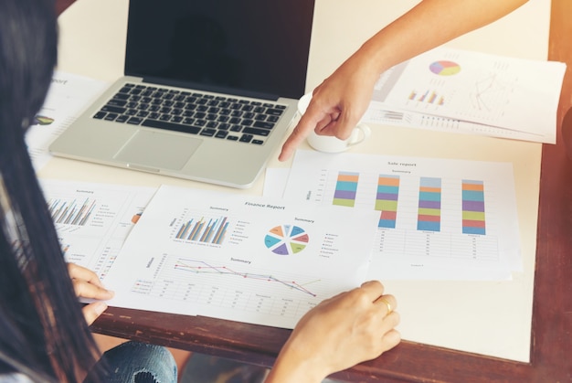 Proceso de trabajo en equipo. Dos mujeres de negocios con portátil y papel gráfico en la oficina de espacios abiertos. Concepto de negocio.