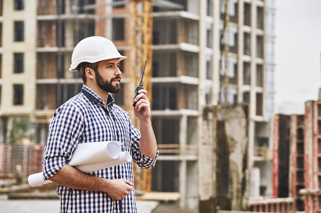 Proceso de trabajo joven profesional en constructor de construcción en casco protector blanco hablando con