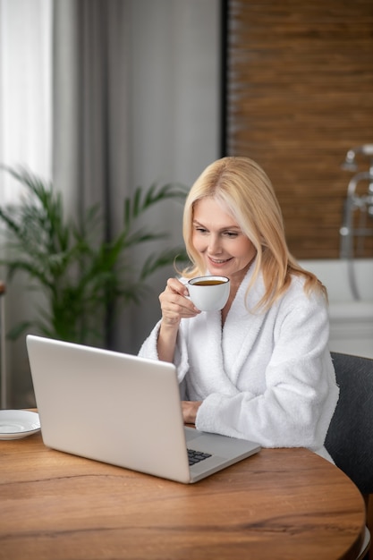 Proceso de trabajo. Mujer bonita rubia sentada en la computadora portátil y mirando pensativa