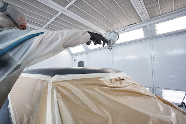 Foto proceso de trabajo del pintor de automóviles en el taller durante la pintura