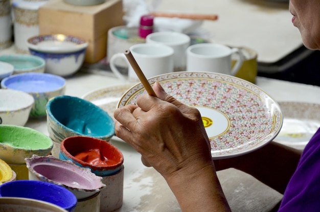 Foto el proceso de trabajo de los tailandeses pinta la cerámica benjarong es una cerámica tradicional tailandesa de cinco colores básicos