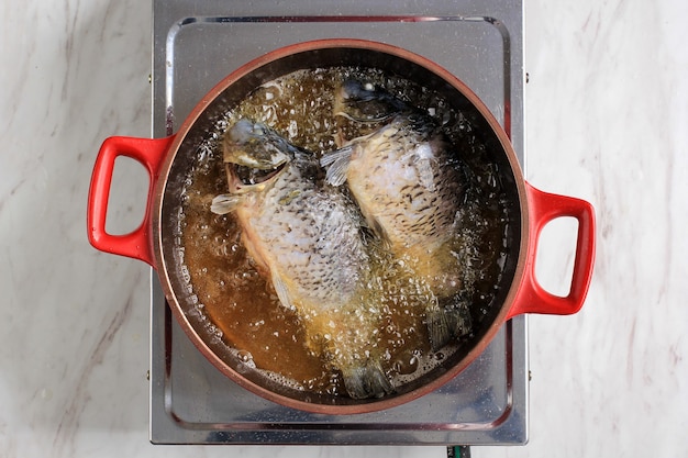 Proceso de vista superior Freír pescado dorado en aceite caliente, cocinar en casa en la cocina Hacer pescado frito con receta asiática