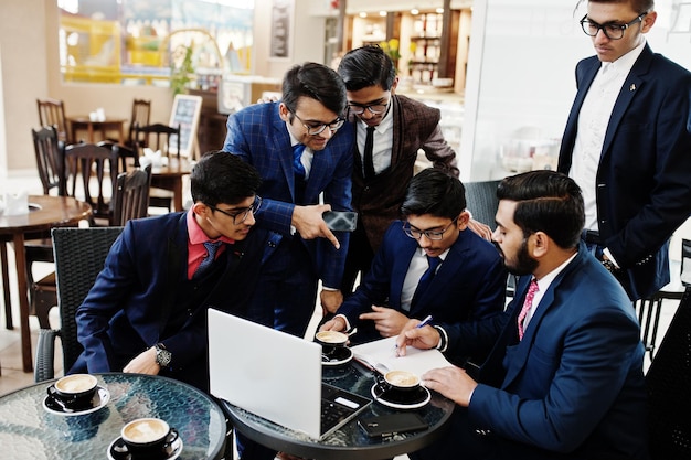 Processo colaborativo de homens de negócios indianos durante reunião de brainstorming no escritórioDiversa equipe de jovens vestidos de terno cooperando no desenvolvimento de um projeto comum