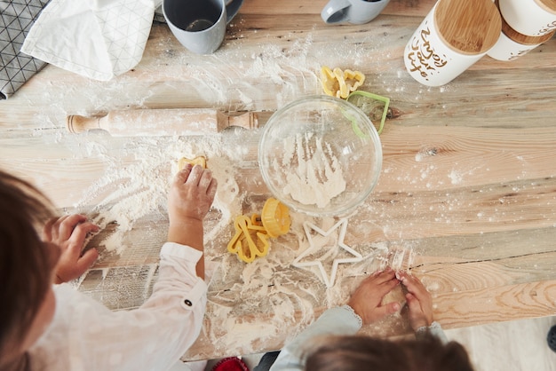 Processo criativo. Vista superior das crianças aprendendo a preparar os alimentos da farinha com instrumentos formados especiais