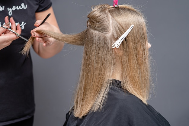 Processo de corte de cabelo feminino para jovem em um salão de cabeleireiro.