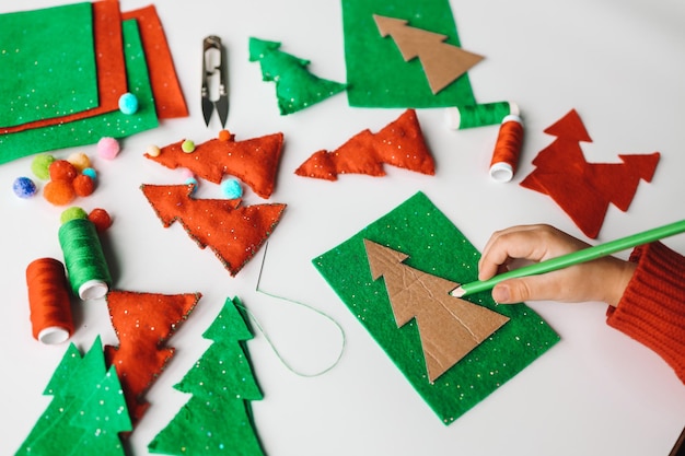 Processo de costura de brinquedos macios feitos à mão com feltro e agulha para decoração de árvores de Natal