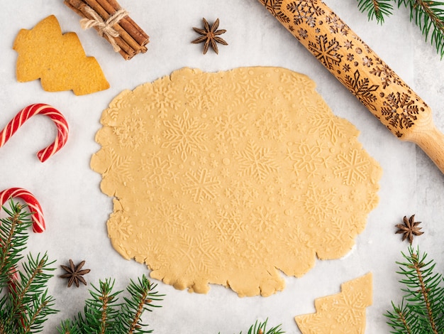 Foto processo de cozimento tradicional sobremesa de natal e ano novo, biscoitos de gengibre, rolo com padrão de flocos de neve, estrelas de anis e canela