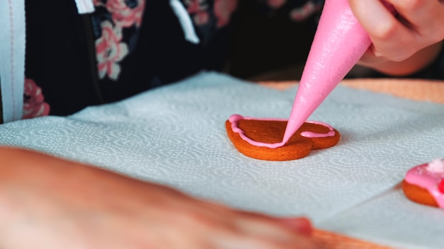 Processo de decoração de biscoitos em forma de coração com esmalte de açúcar rosa para fazer comida festiva