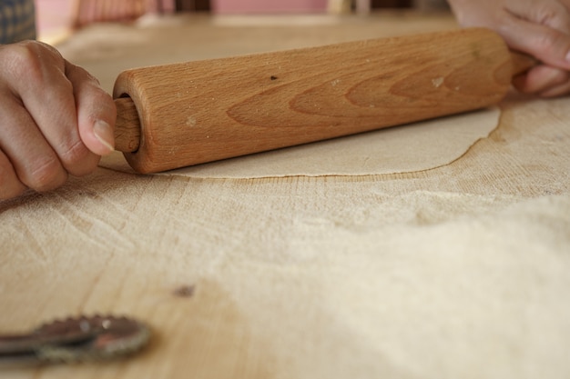 Processo de fabricação de massas farfalle veganas caseiras. o cozinheiro usa um rolo para esticar a massa