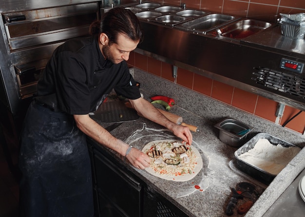 Foto processo de fabricação de pizza italiana fresca homem fazendo pizza na cozinha