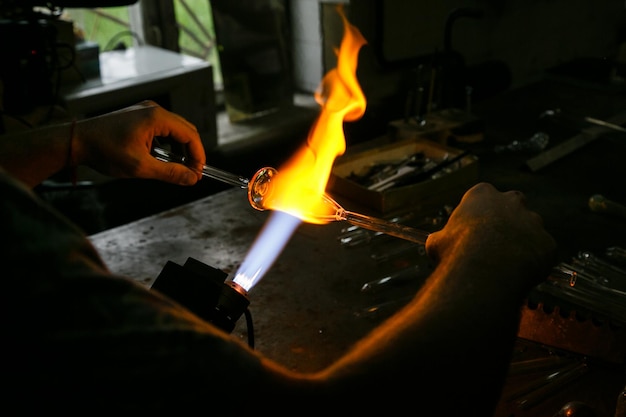 Processo de fabricação de sopro de vidro. O fogo aquece o vidro em branco com queimador de sopro de vidro. Vidrarias artesanais