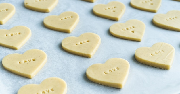 Processo de fazer biscoitos em forma de coração com a palavra amor prontos para assar. conceito de pastelaria.